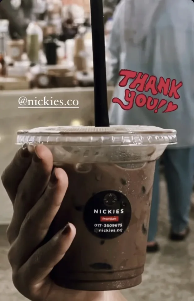 Customer holding a Nickies Premium iced chocolate, with a red “Thank you!” sticker