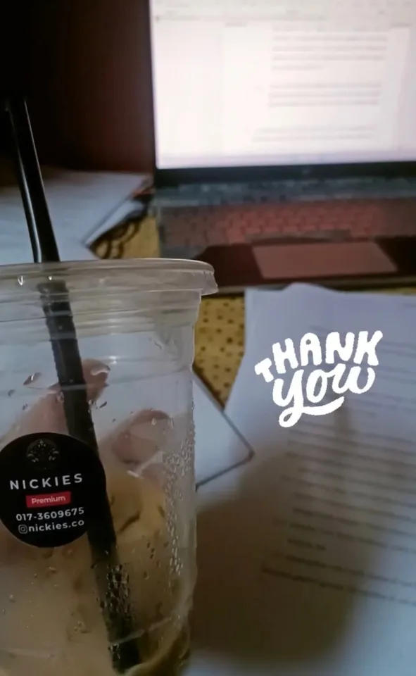 Finished Nickies iced drink beside a laptop and handwritten notes
